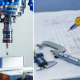 Макро фотография элементов металлообрабатывающего оборудования на производстве оптических приборов, фото инженерных инструментов на фоне инженерных чертежей и схем