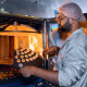 Фотосъемка производства объективов марки Zeiss в Минске, портрет сотрудника-лаборанта крупным планом, которые достаёт заготовки линз из горячего сушильного шкафа