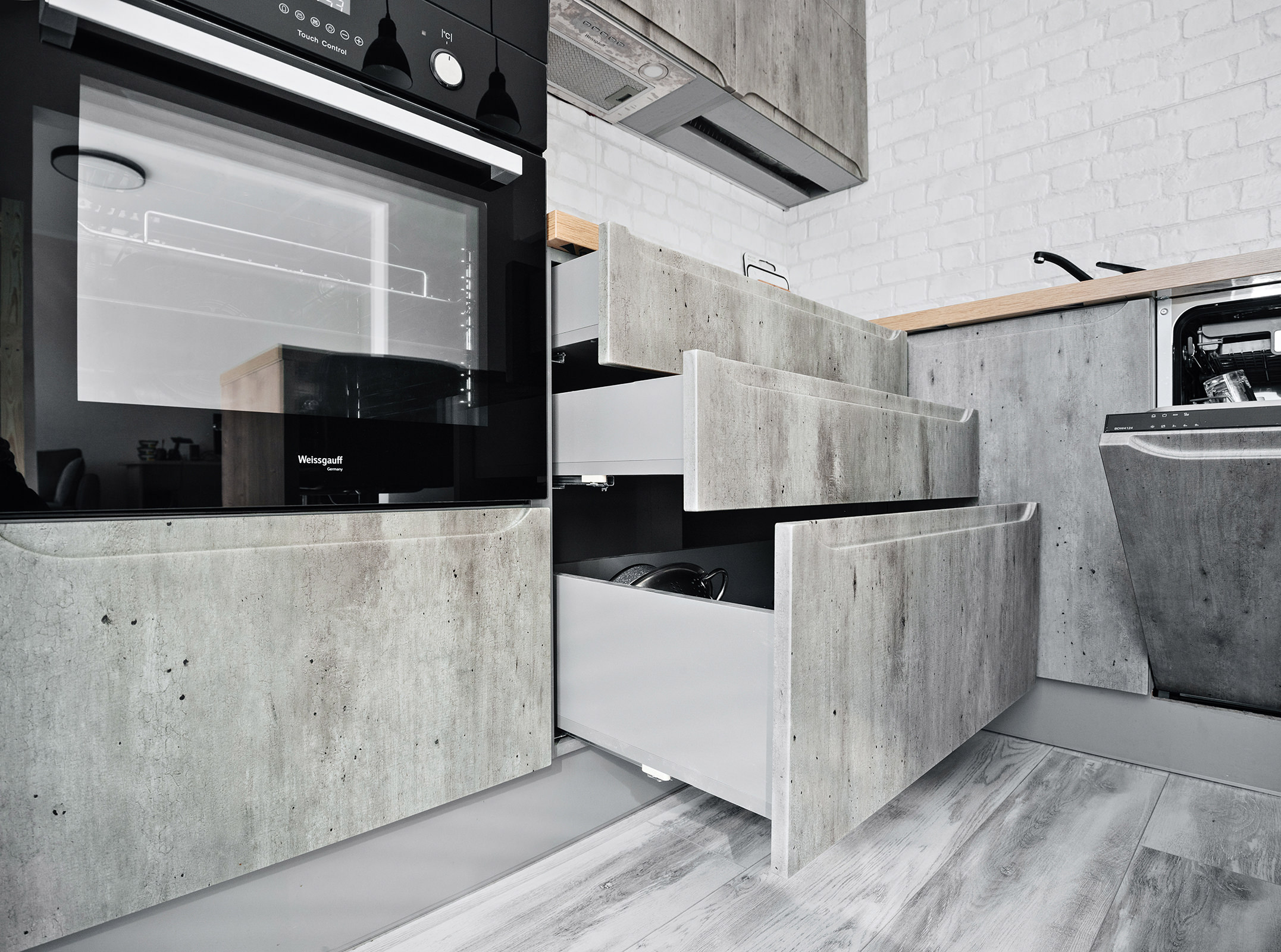 Фотография кухонной мебели в современном стиле цвета и фактуры бетон с выдвижными ящиками и встроенной бытовой кухонной техникой