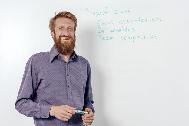 Съемка делового портрета работника IT компании в офисе на фоне доски во время обсуждения проекта