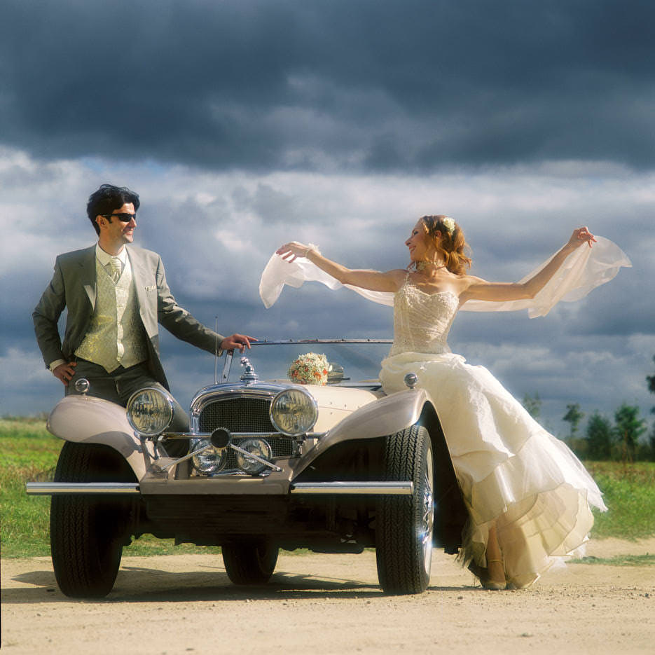 Свадебный фотограф сделал красивый портрет пары возле ретро автомобиля на фоне тёмного неба