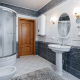 Фотография интерьера ванной комнаты и туалета в светло-серых тонах с душевой кабиной, умывальником, зеркалом и электрическим водонагревателем