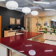 Фотосъёмка интерьеров офиса для портфолио архитектурной и строительной компании, красный изогнутый стол с отражением круглых светильников на глянцевой поверхности