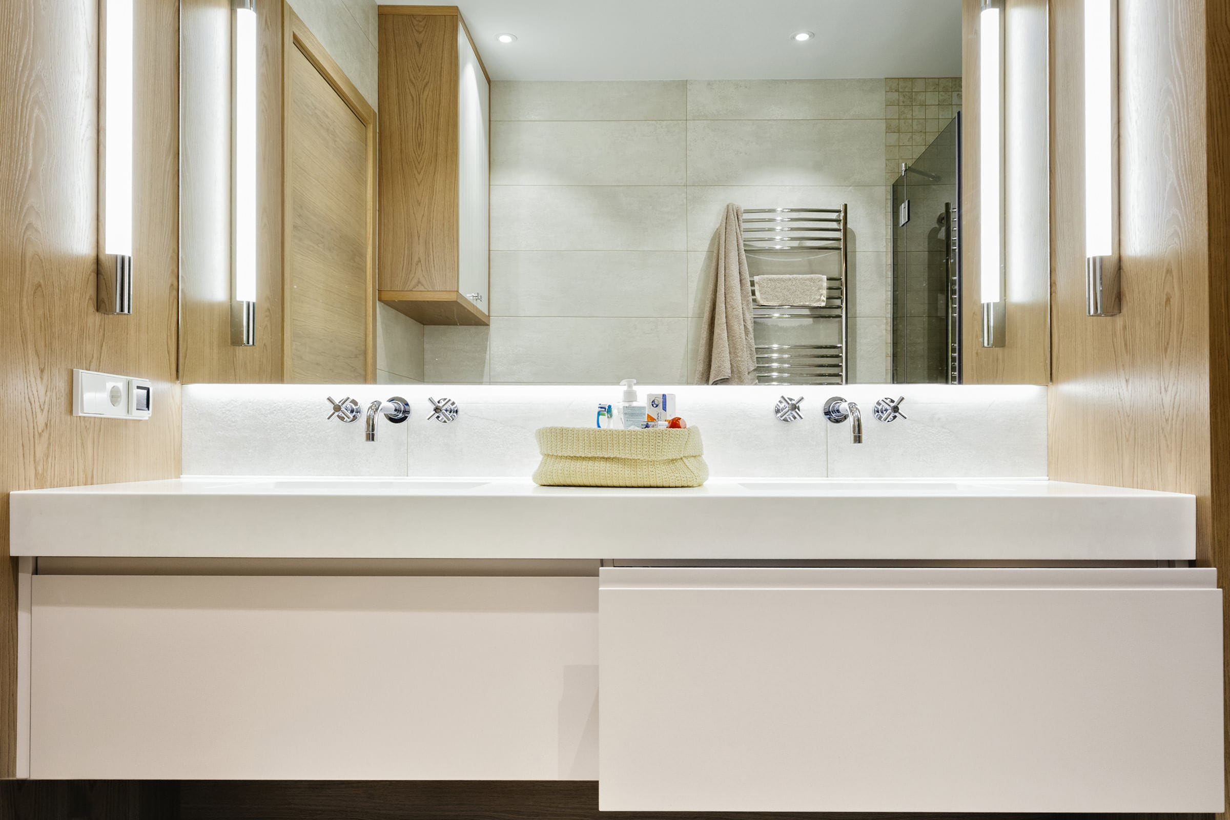 Интерьерное фотография ванной комнаты с умывальником, большим зеркалом с подсветкой и душевой кабиной для портфолио изготовителя элитной деревянной мебели