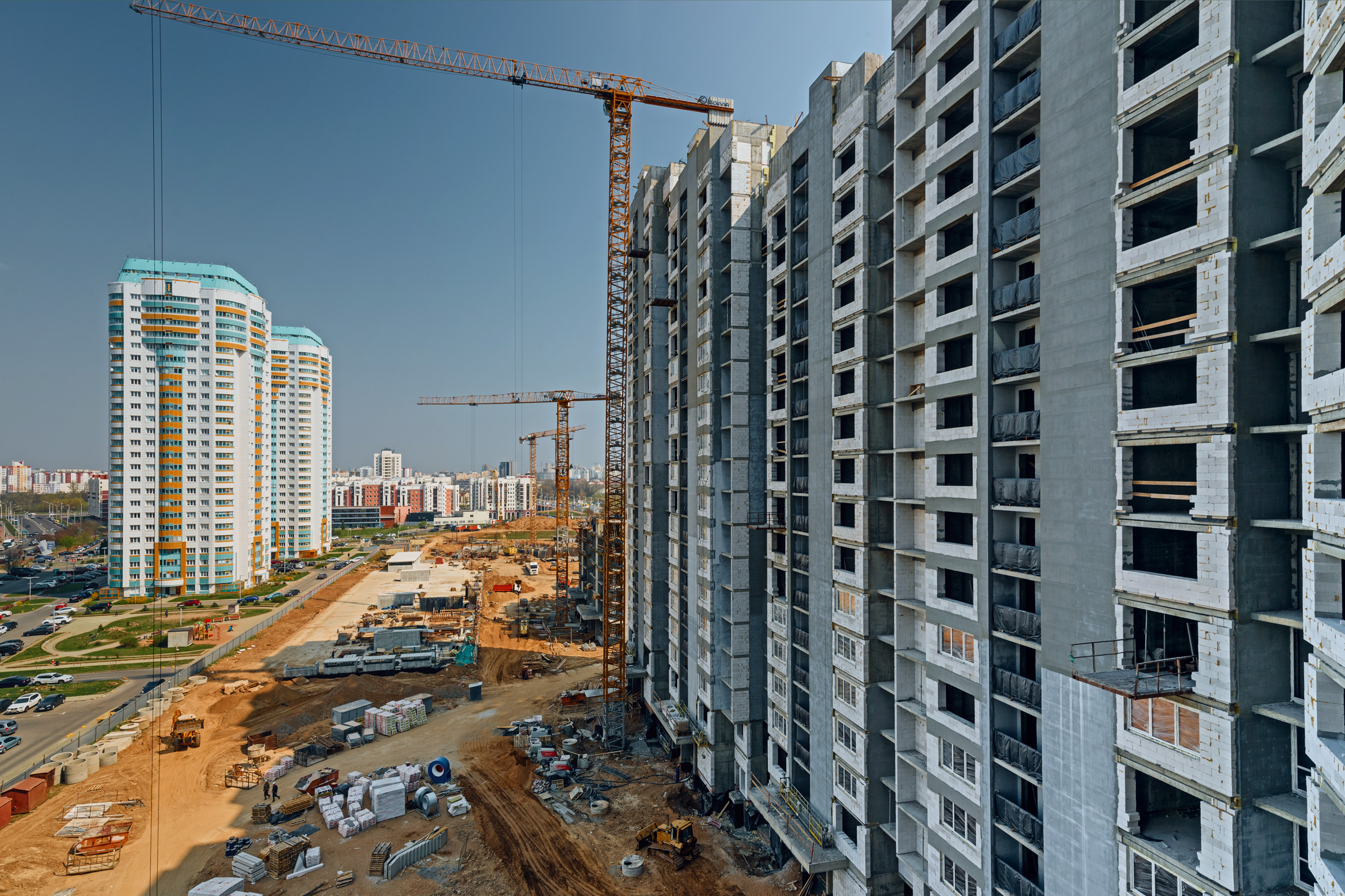 Фотосъёмка процесса строительства многоэтажного жилого комплекса, фото панельного дома с башенными кранами на площадке